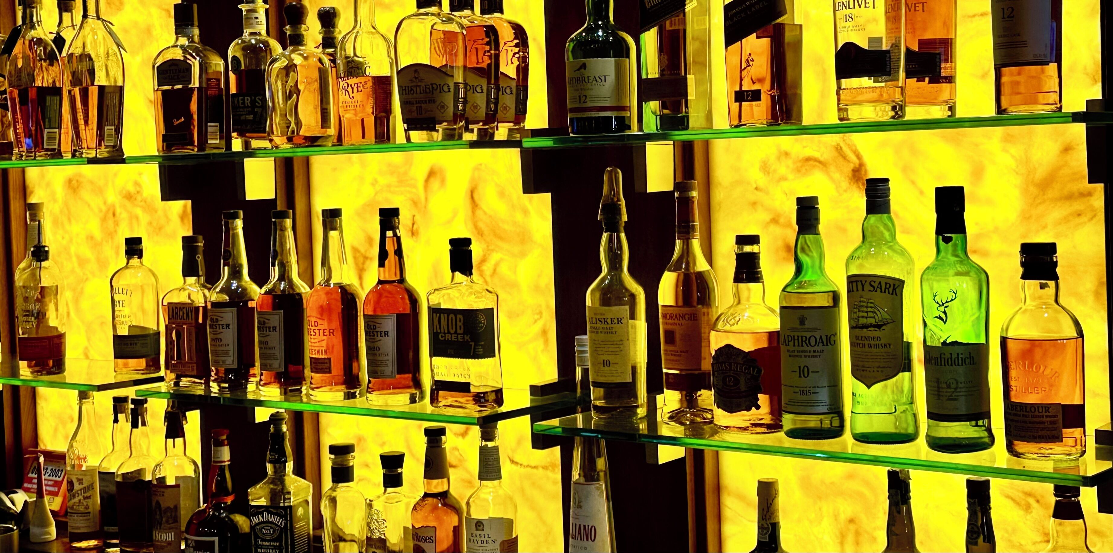 A bar with multiple shelves of various liquor bottles.