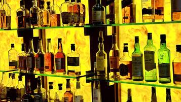 A bar with multiple shelves of various liquor bottles.