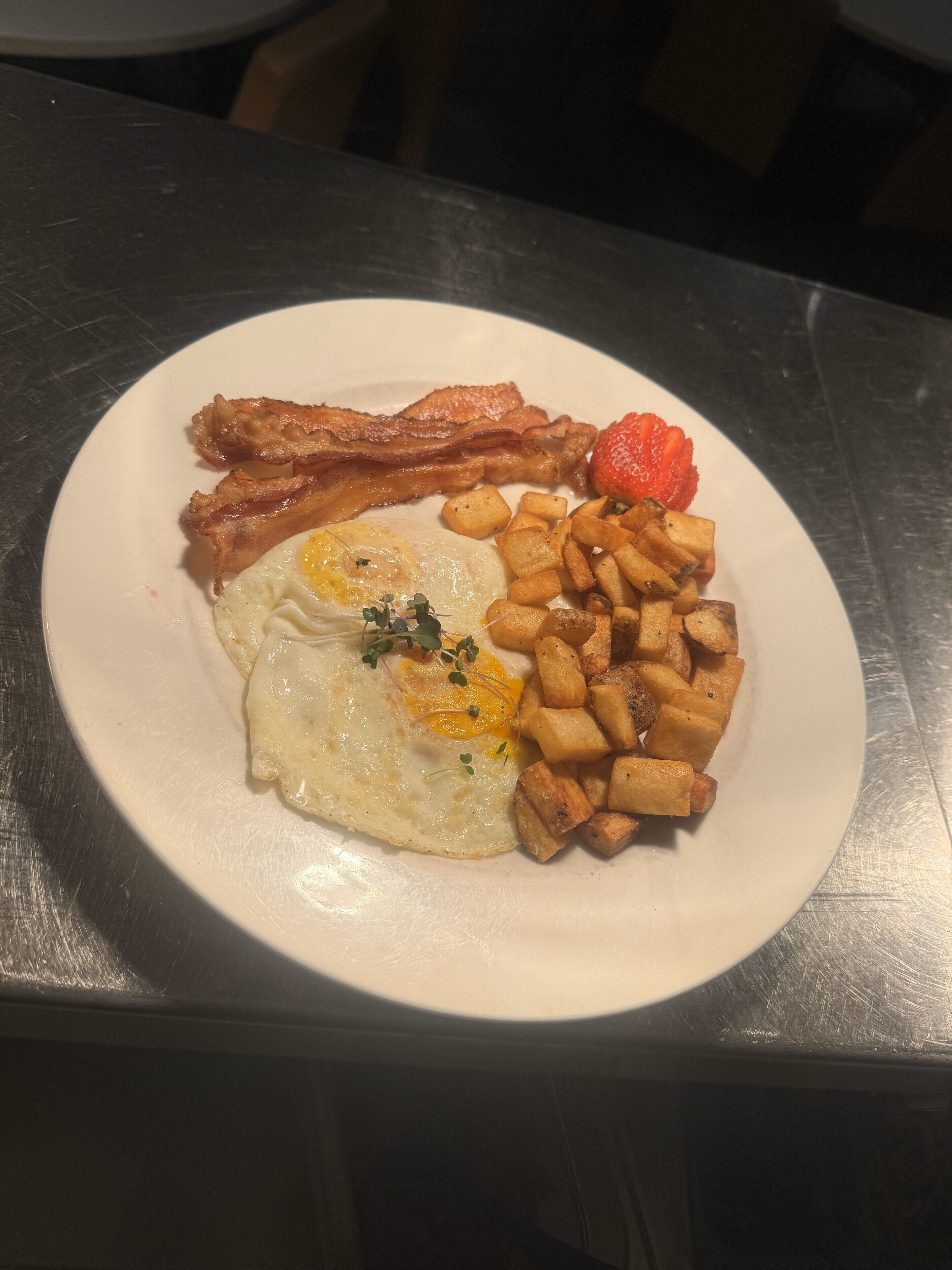 Une assiette de bacon, d'œufs et de pommes de terre.