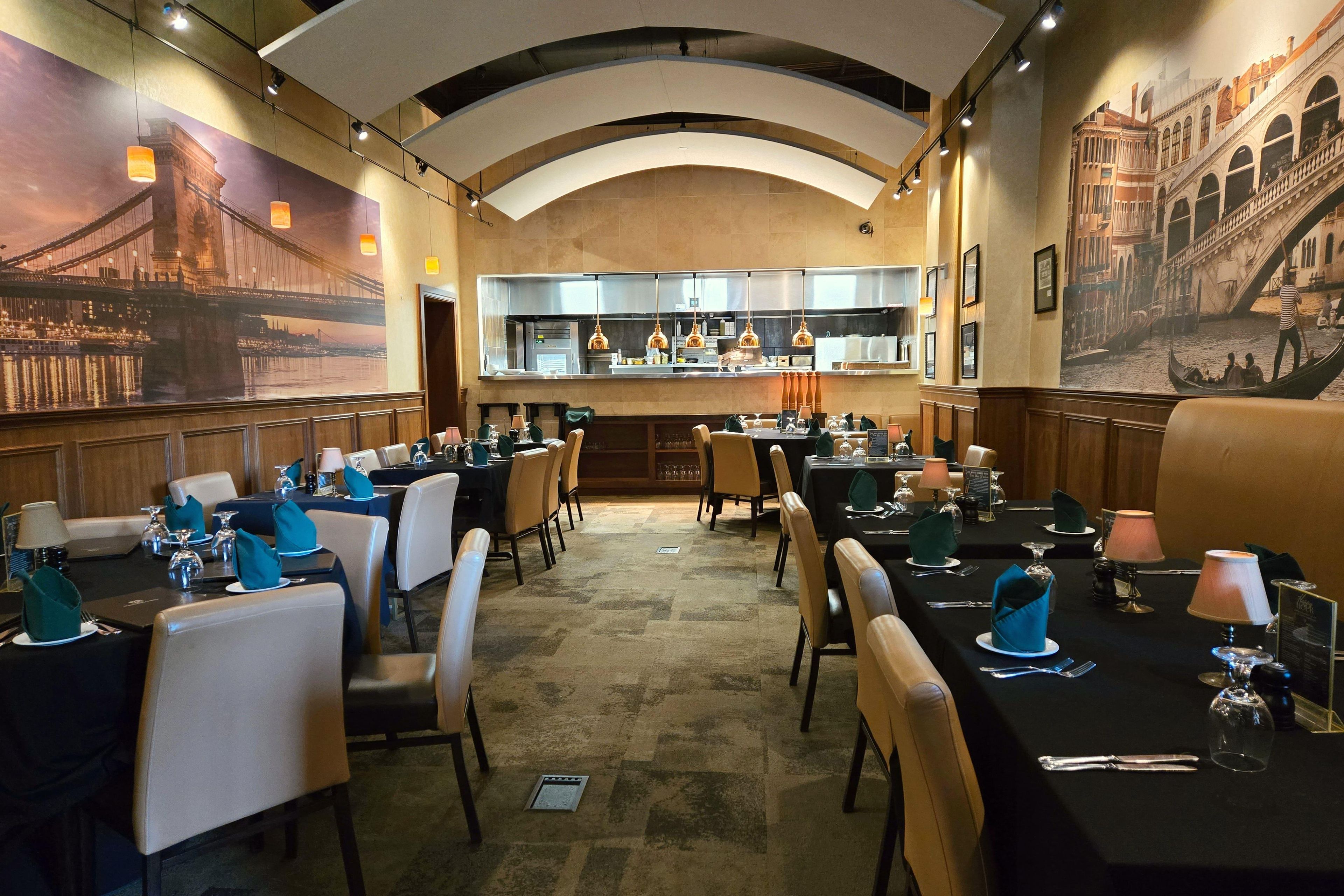 A restaurant with multiple dining tables, chairs, and a kitchen area in the background.