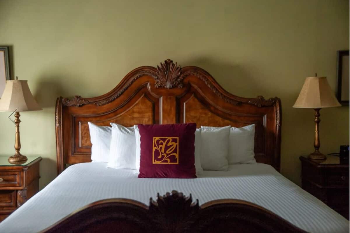 Una cama bien hecha con cabecera de madera, ropa blanca de cama y una almohada decorativa.