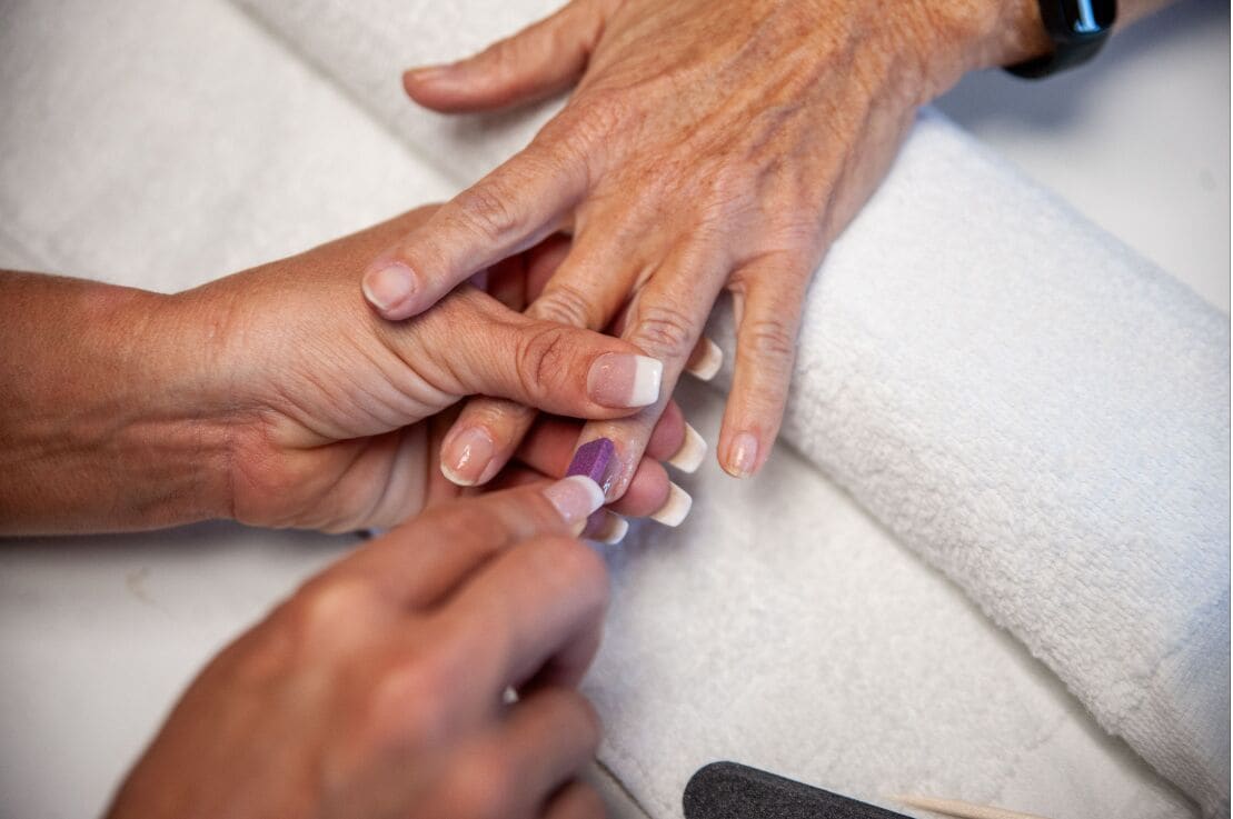 Primer plano de manos, una con un reloj y la otra con una manicura.