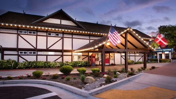 A traditional building with a covered entrance, American and Danish flags, and a sign for "The King Frederik's".