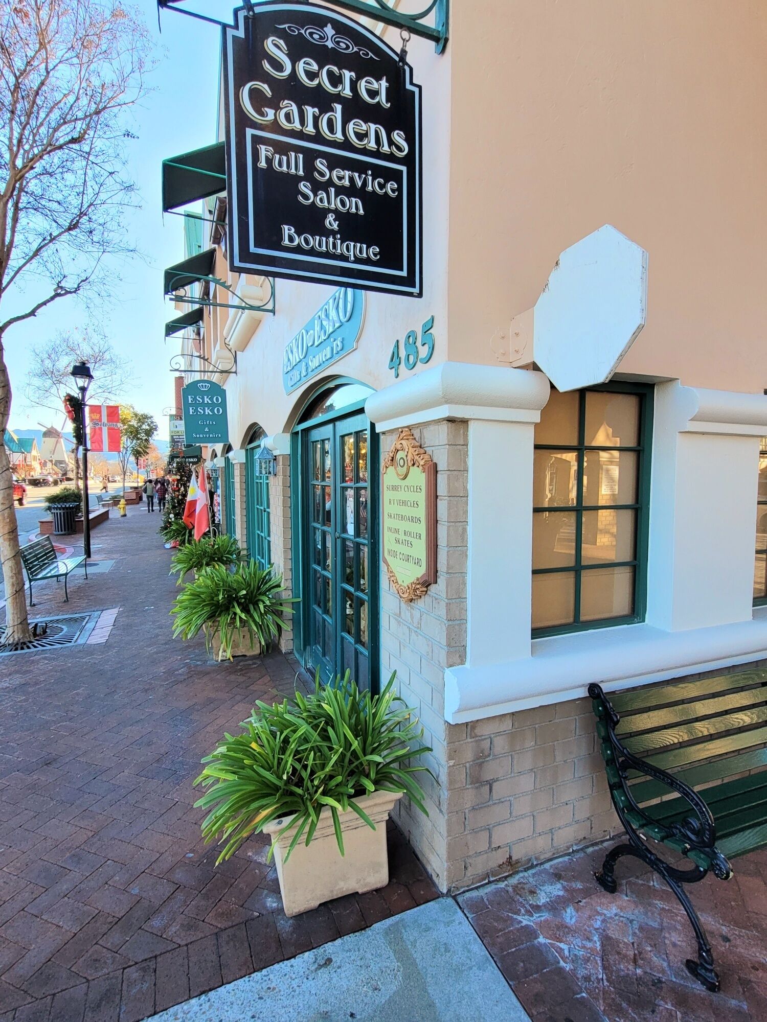 A building with a sign for 'Secret Gardens Full Service Salon & Boutique' and a plaque for 'Esko Esko Gifts & Souvenirs'.