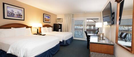A hotel room with two beds, a desk, a chair, a TV, and a balcony with a view.