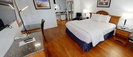A hotel room with a bed, desk, chair, and a mirror.