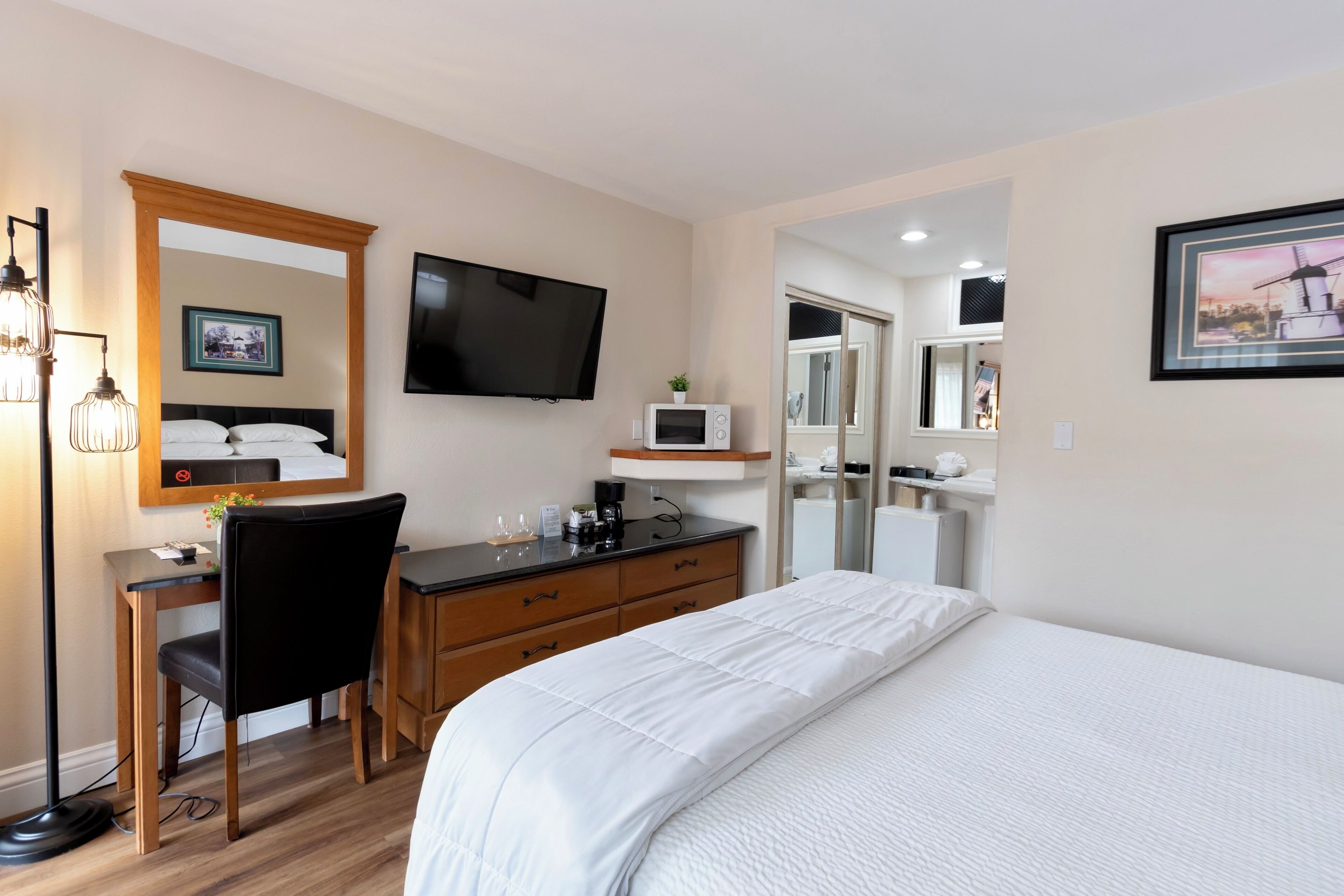 A hotel room with a bed, desk, chair, television, and a microwave.