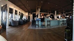 A spacious bar area with high ceilings and pendant lighting, a central bar counter, and seating arrangements.