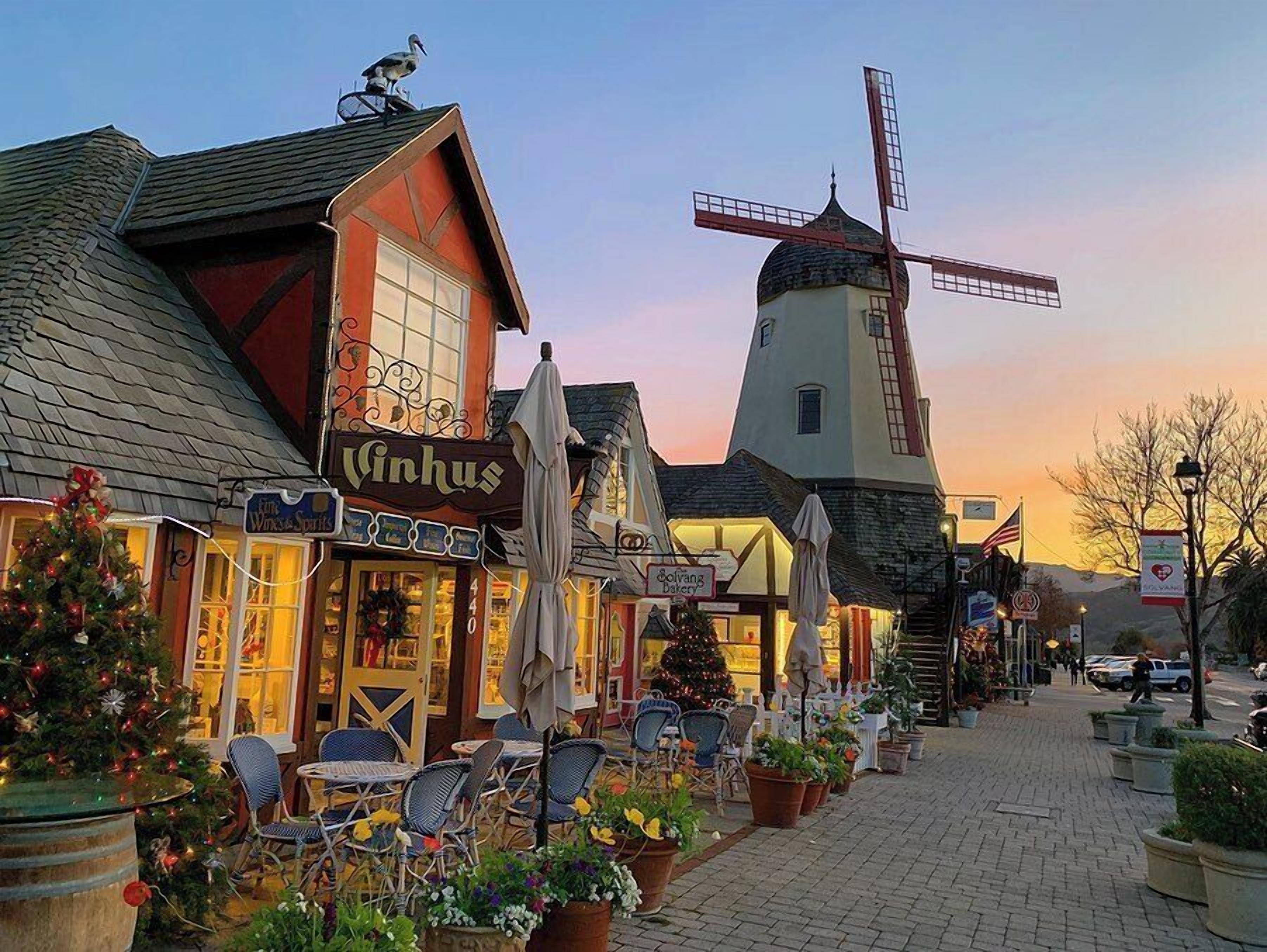 A traditional windmill, a bakery, and a Christmas tree in a quaint village setting.