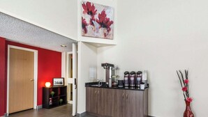 A modern kitchen with dark wood cabinets, a coffee station, and a red vase with flowers. - Comfort Inn Thetford Mines (Thetford Mines)