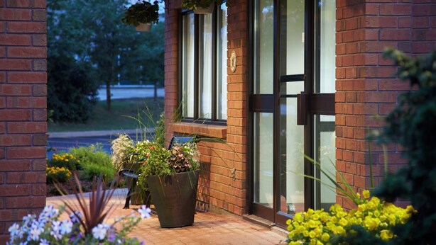 A brick building with large windows and a door, surrounded by potted plants and flowers. - Comfort Inn Thetford Mines (Thetford Mines)