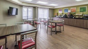 A dining area with tables and chairs, a kitchen counter with appliances, and a television mounted on the wall. - Comfort Inn Thetford Mines (Thetford Mines)