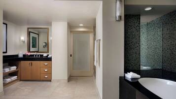 A modern bathroom with a large bathtub, a vanity with a mirror, and a shower area.