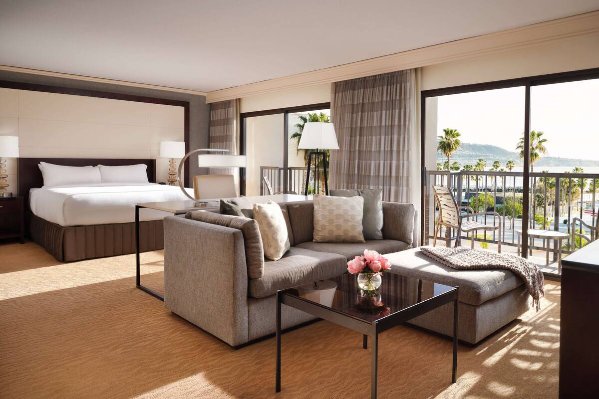 Une chambre d’hôtel avec un lit, un canapé et un balcon offrant une vue.