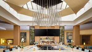 Un grand espace bar doté d’un haut plafond, d’un comptoir central et de différents types de sièges.
