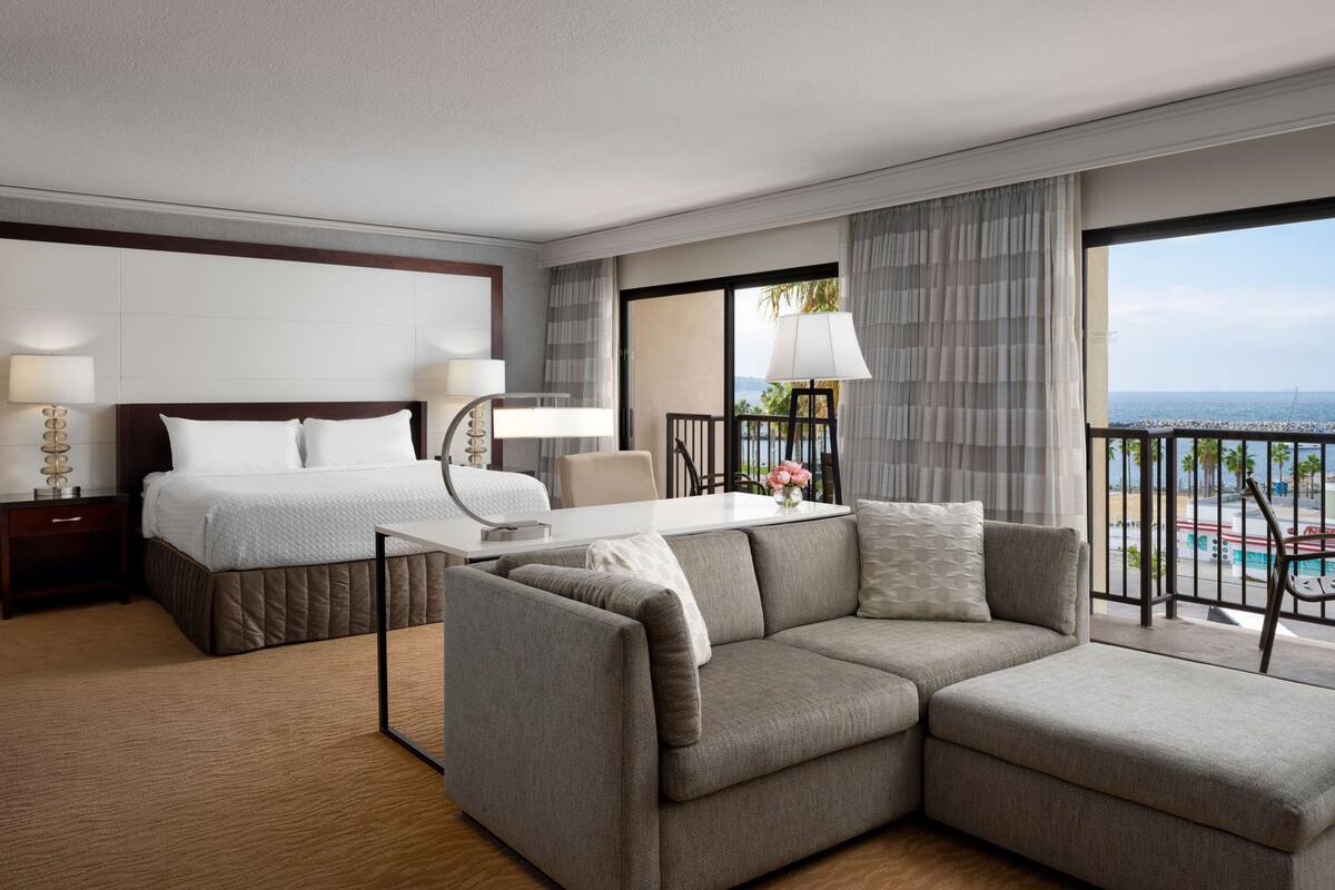 Une chambre d’hôtel moderne équipée d’un lit, d’un canapé, d’une table à manger et offrant une vue sur l’océan.
