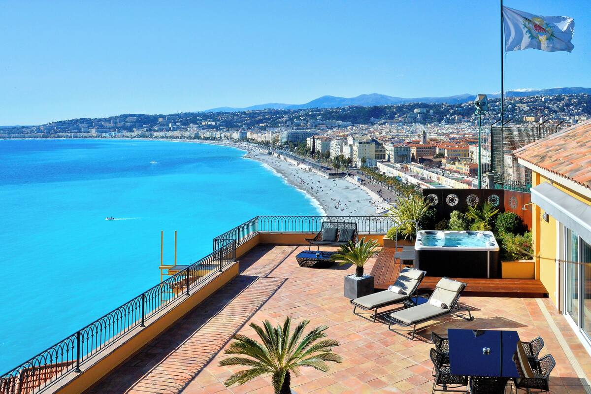 A rooftop terrace with a pool, lounge chairs, and a view of the beach and cityscape.