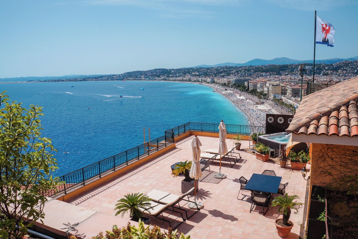 A rooftop terrace with outdoor seating, a pool, and a view of the coastline.