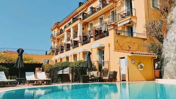 Un hotel con piscina, mobiliario exterior y balcones.