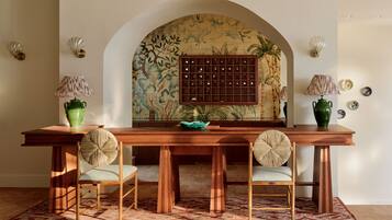 A dining area with a wooden table, two chairs, and a decorative wall with a tiled pattern.