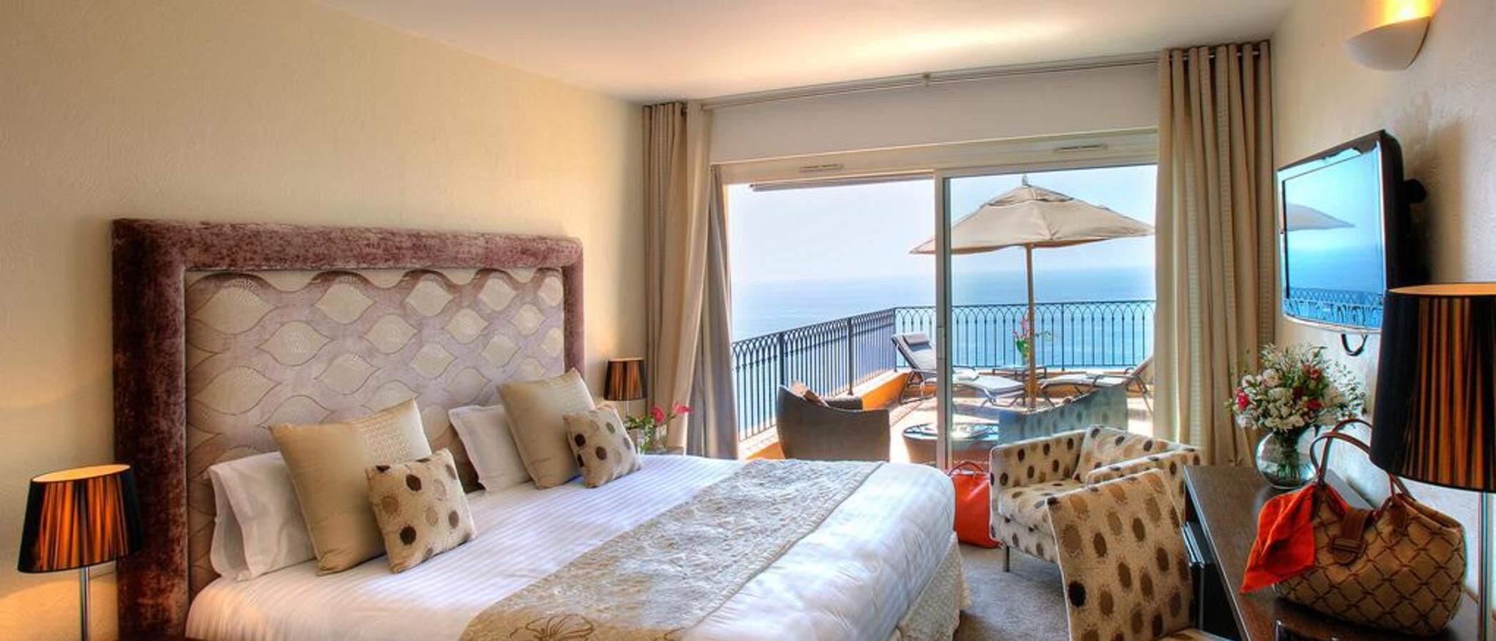 A hotel room with a large bed, a balcony with a view, and a TV.