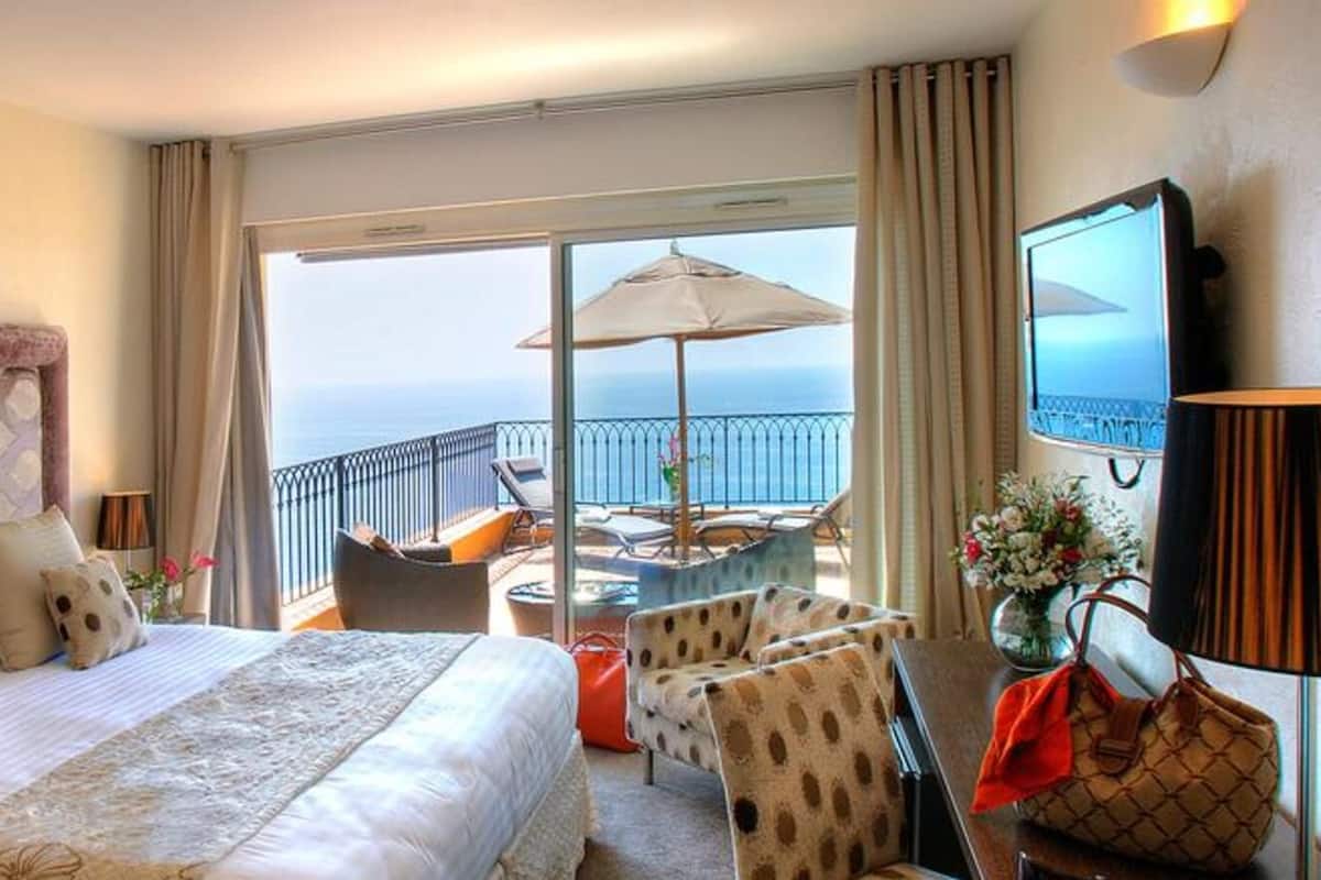 A hotel room with a large bed, a balcony with a view, and a TV.
