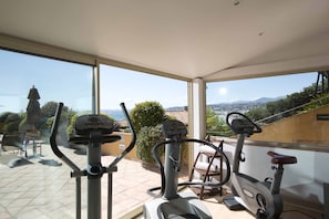 A home gym with exercise equipment and a view of the city and mountains.