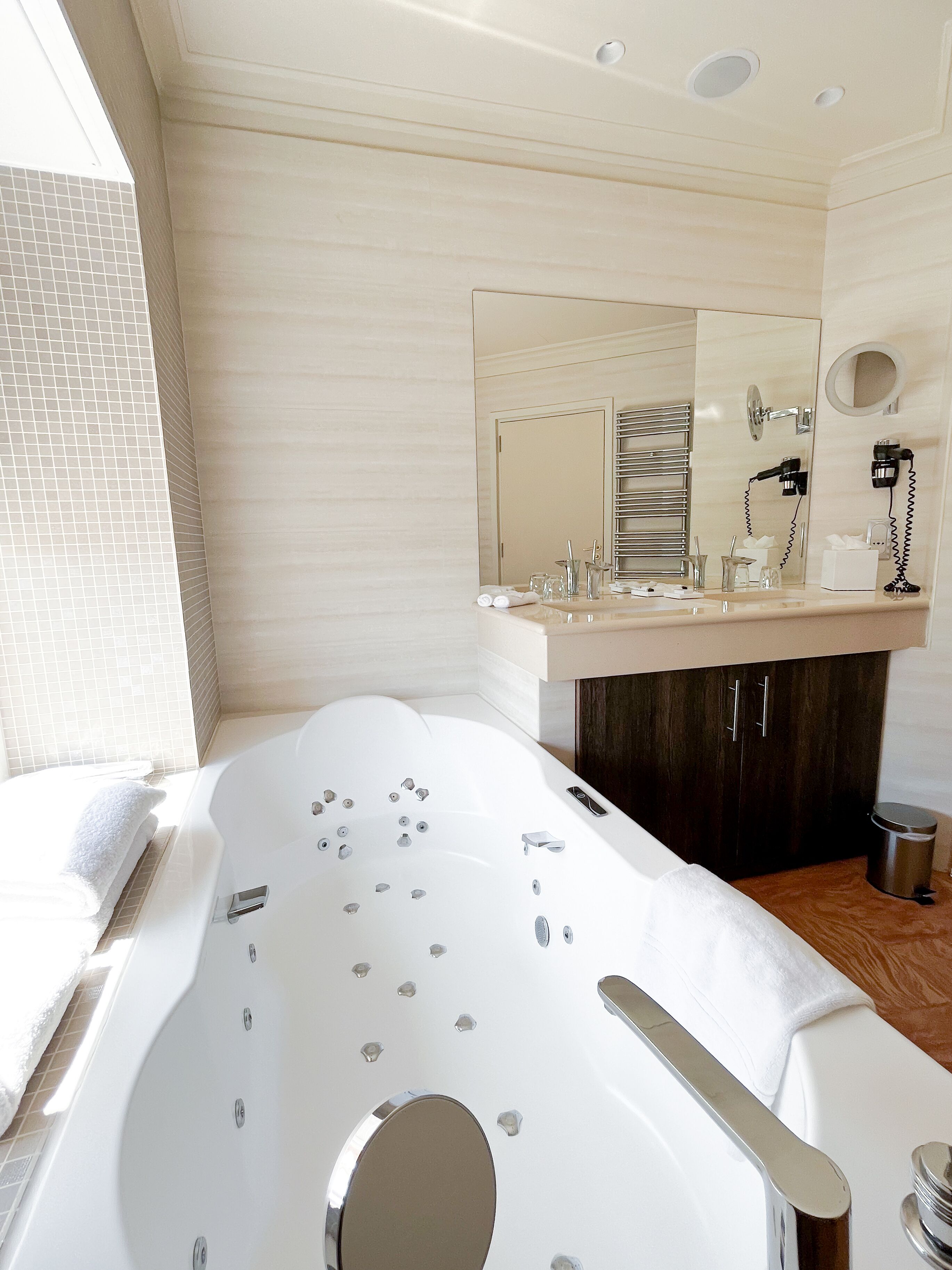 A modern bathroom with a large bathtub, a vanity with a mirror, and a towel rack.
