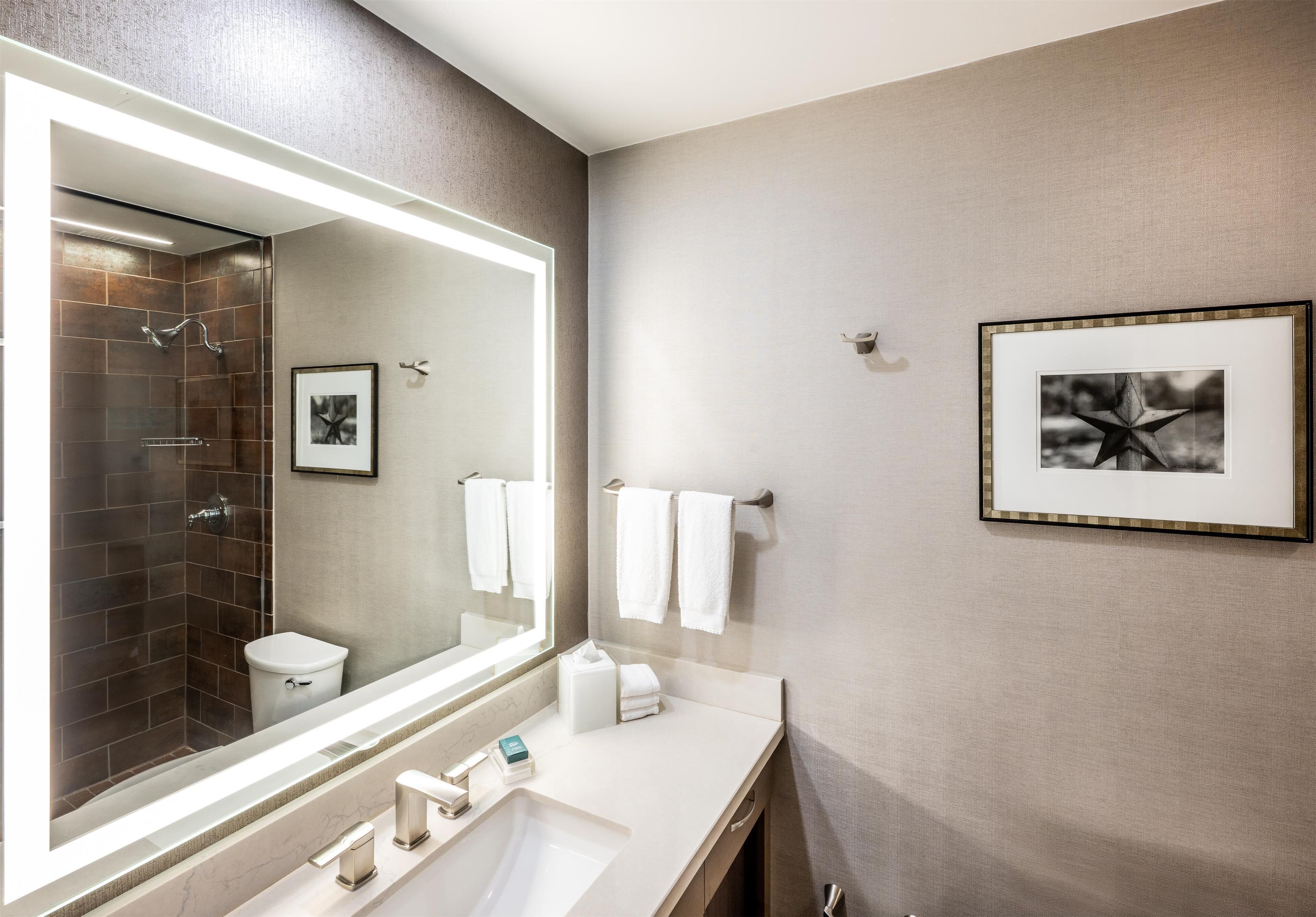 Een moderne badkamer met een grote spiegel, douche en wastafel.