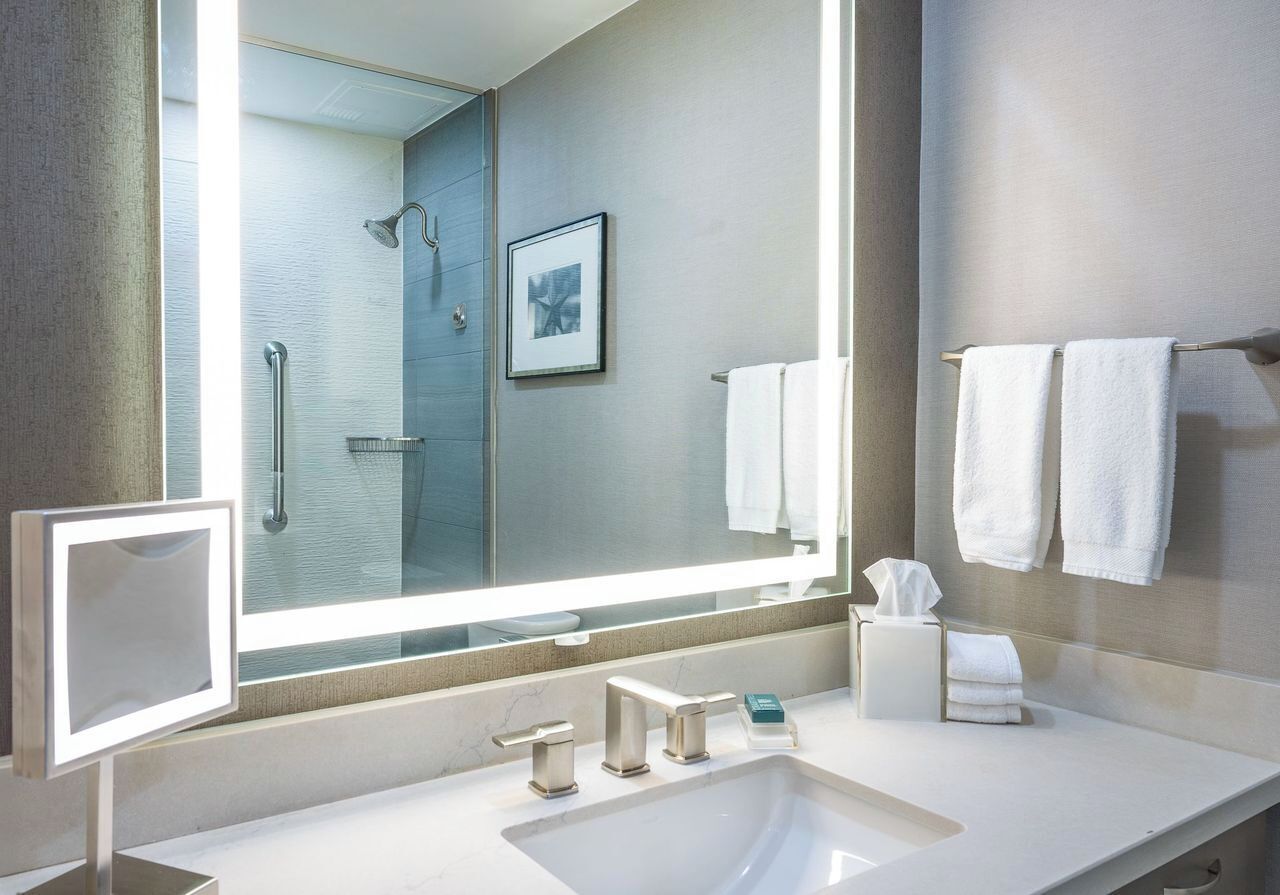 A modern bathroom with a large mirror, a sink, and a shower.