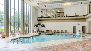 An indoor swimming pool with lounge chairs and potted plants.