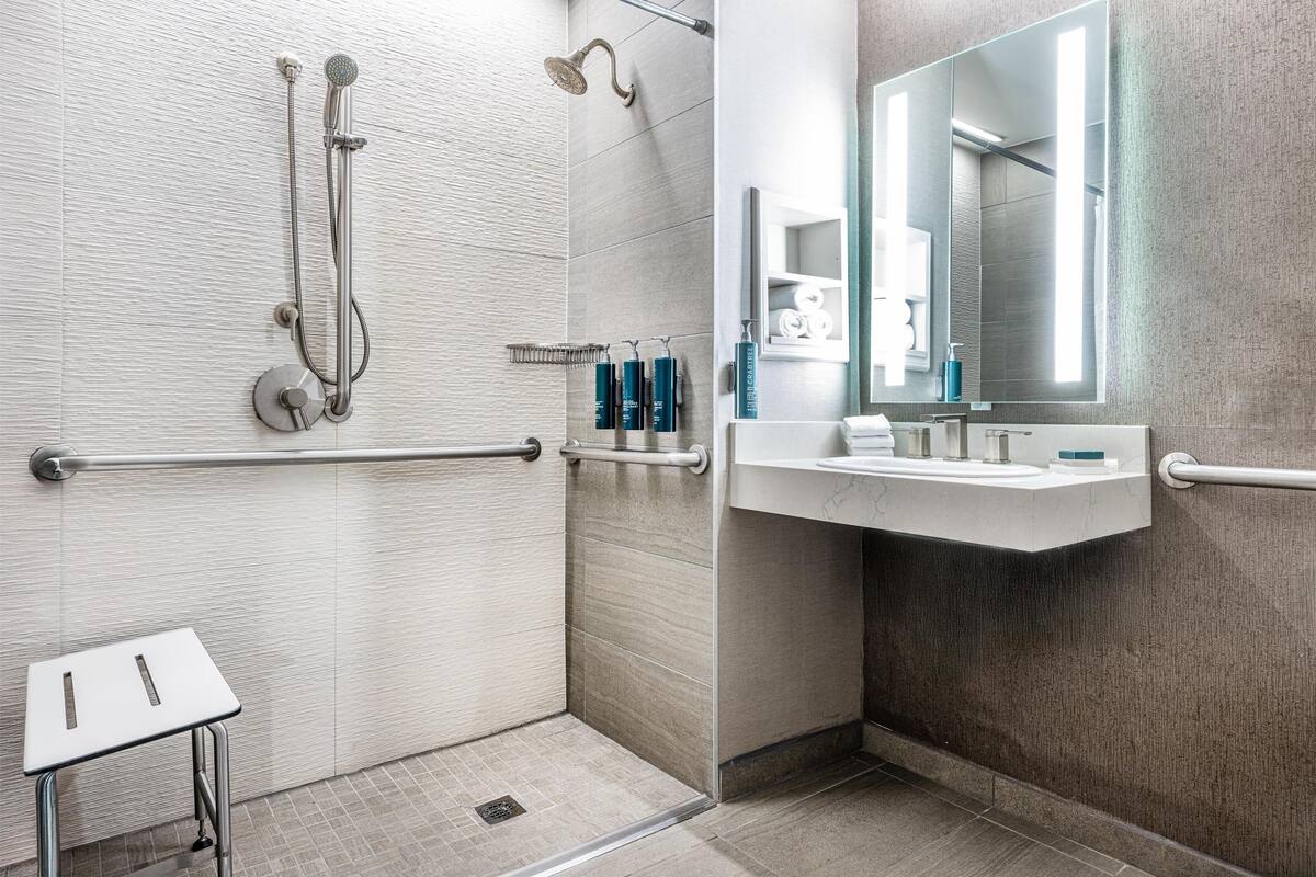 A modern bathroom with a shower, a sink, and a mirror.
