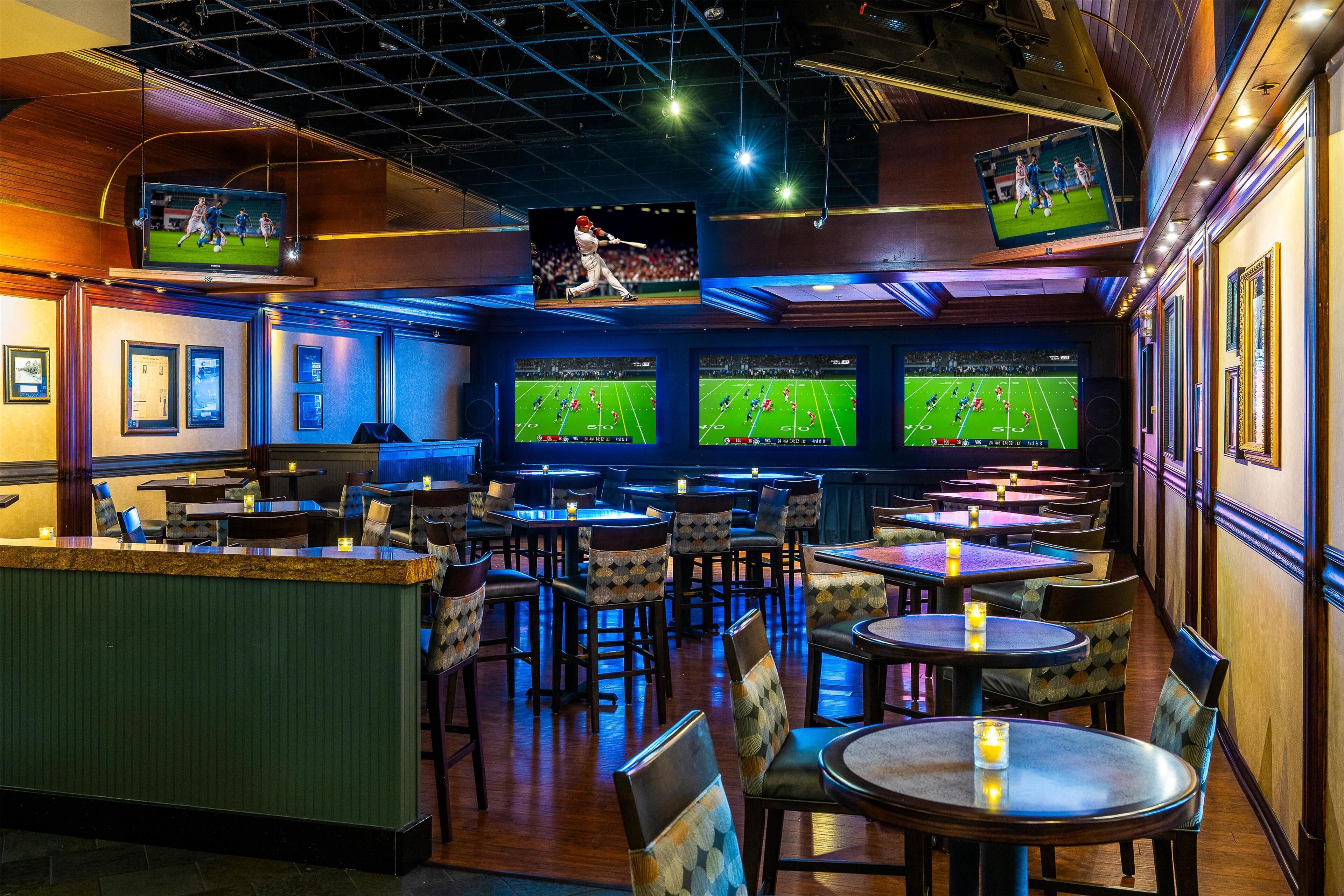 Un bar deportivo con varias pantallas mostrando partidos, decoración de madera y una zona de bar.