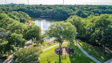 An aerial view of a park with a river, walking paths, and a central circular garden.