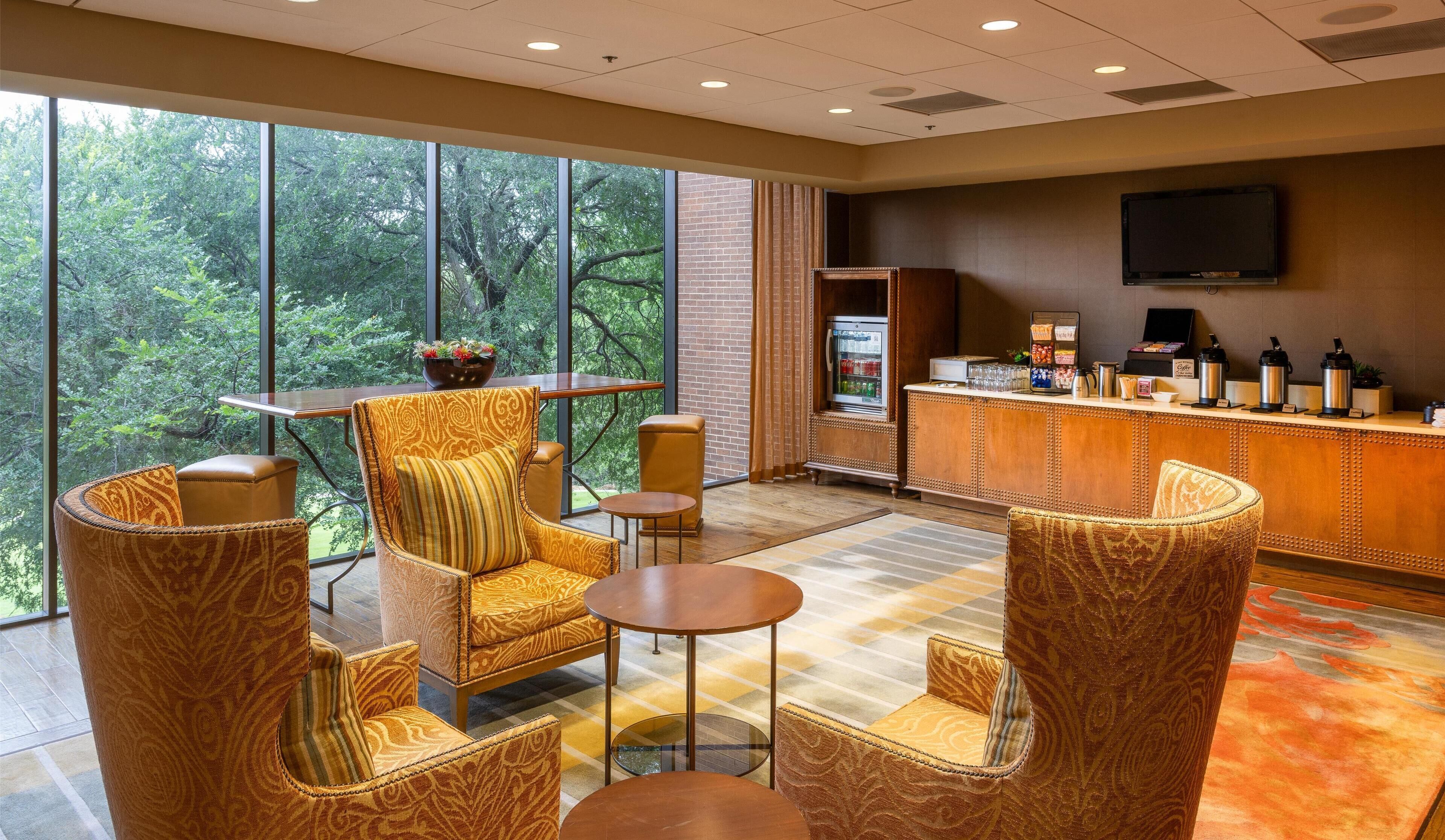 A hotel lobby with large windows, a bar area, and seating arrangements.