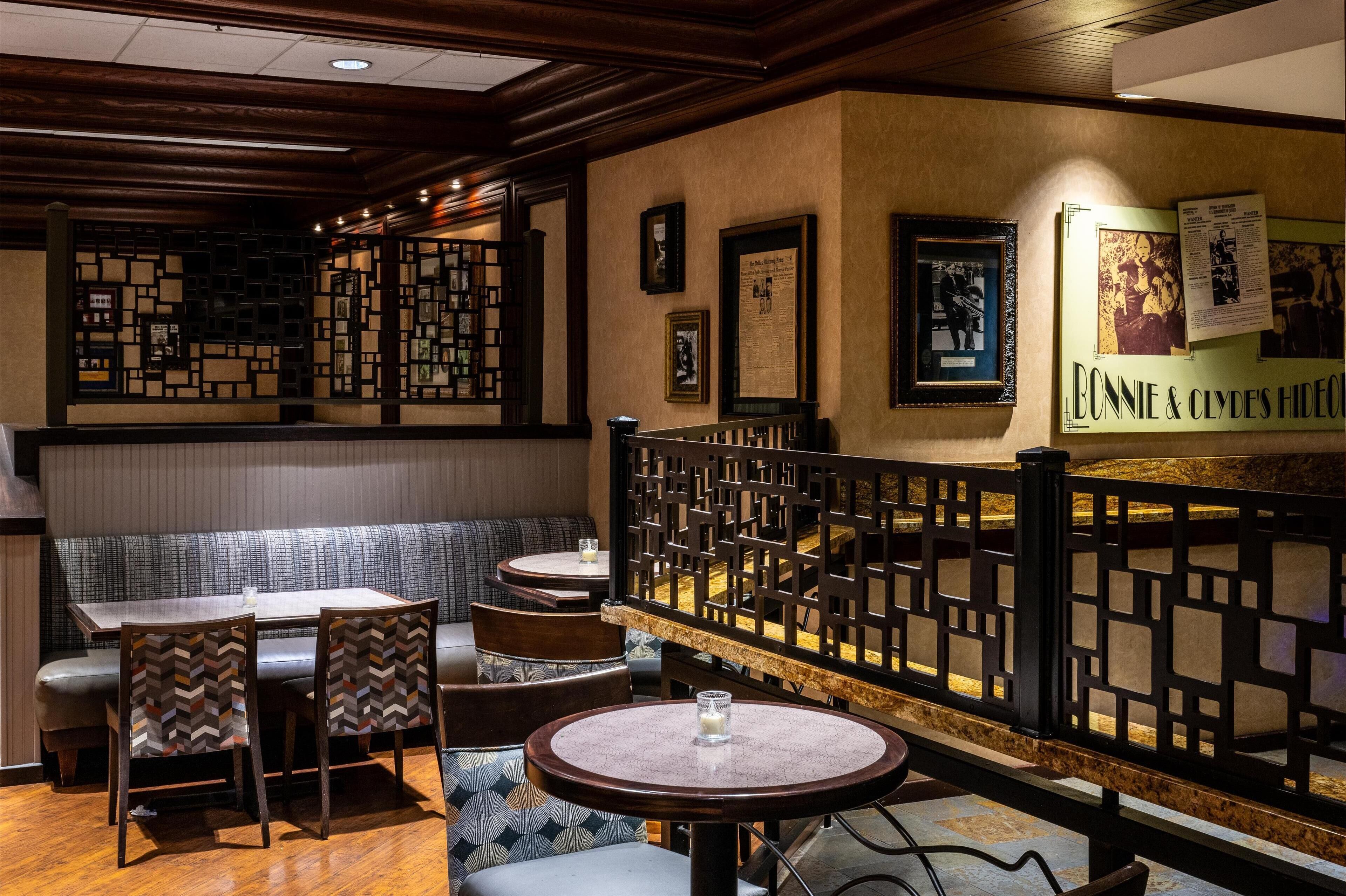 A restaurant with wooden furniture, a low partition wall, and framed pictures on the wall.