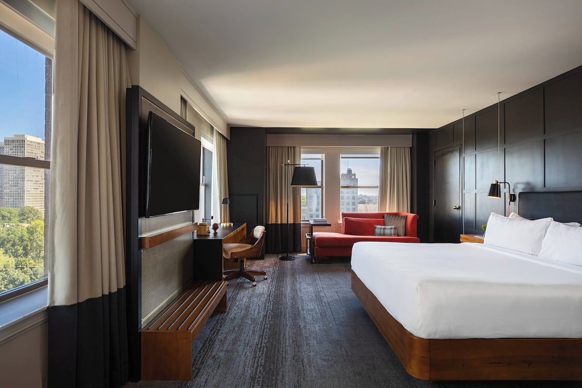 Une chambre d’hôtel avec un grand lit, un bureau avec une chaise, un canapé rouge et un téléviseur.