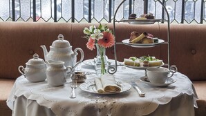 A table set with tea service, a vase with flowers, and a tiered dessert stand. - Claridge Hotel (Buenos Aires)