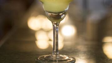 Un cóctel en una copa de martini con pajita sobre una barra.