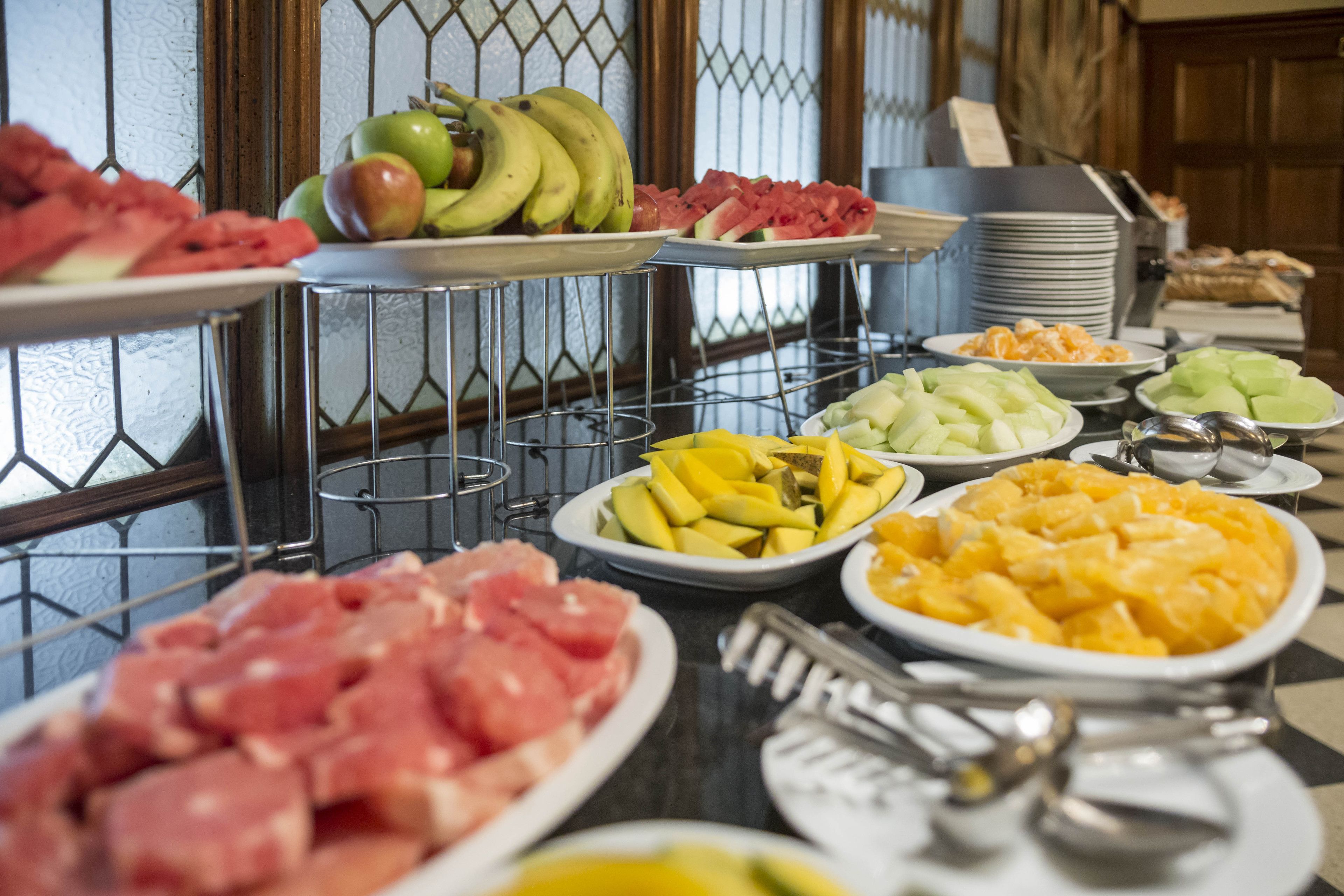 A buffet with various fruits, meats, and cheeses.