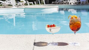 A poolside setting with lounge chairs and a glass of cocktail with fruit garnish. - Claridge Hotel (Buenos Aires)