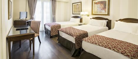A hotel room with two single beds, a desk with a computer, a chair, and a TV.