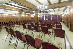 Un amplio salón con filas de sillas rojas y paneles de madera.