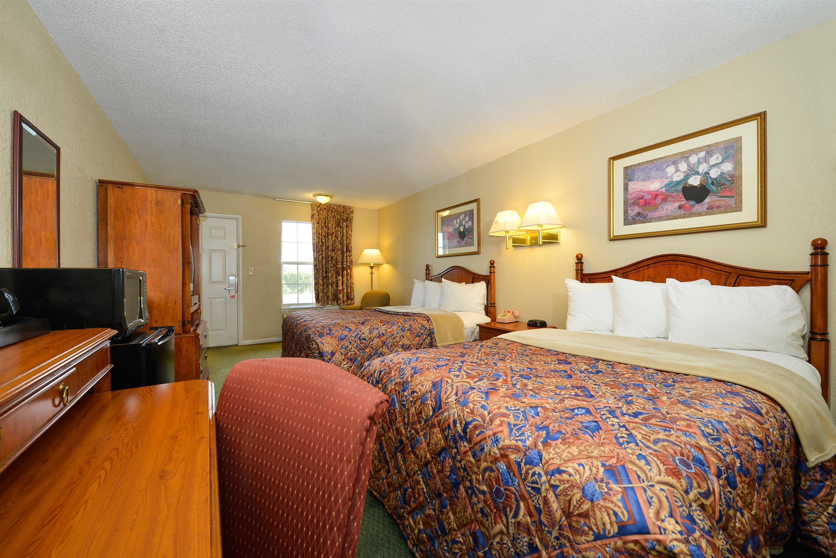 A hotel room with two beds, a TV, a desk, and a chair.