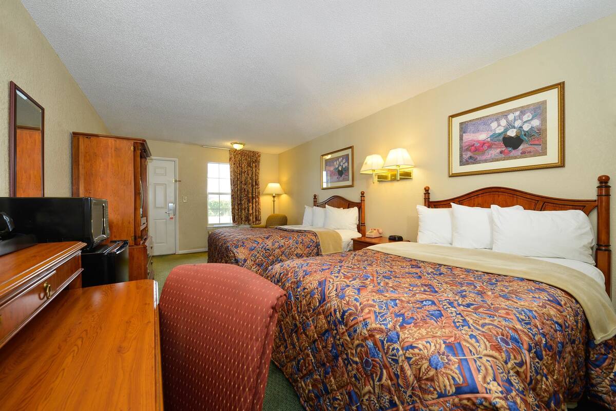 A hotel room with two beds, a TV, a desk, and a chair.