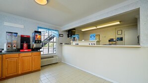 Une cuisine équipée d’une machine à café, d’un four à micro-ondes et d’un distributeur de café. Il y a une fenêtre donnant sur un escalier et une porte.