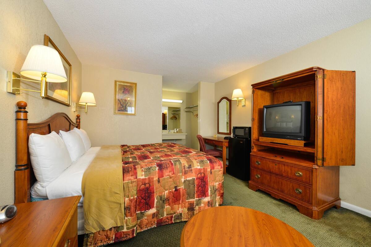 A hotel room with a bed, a desk, a television, and a mirror.