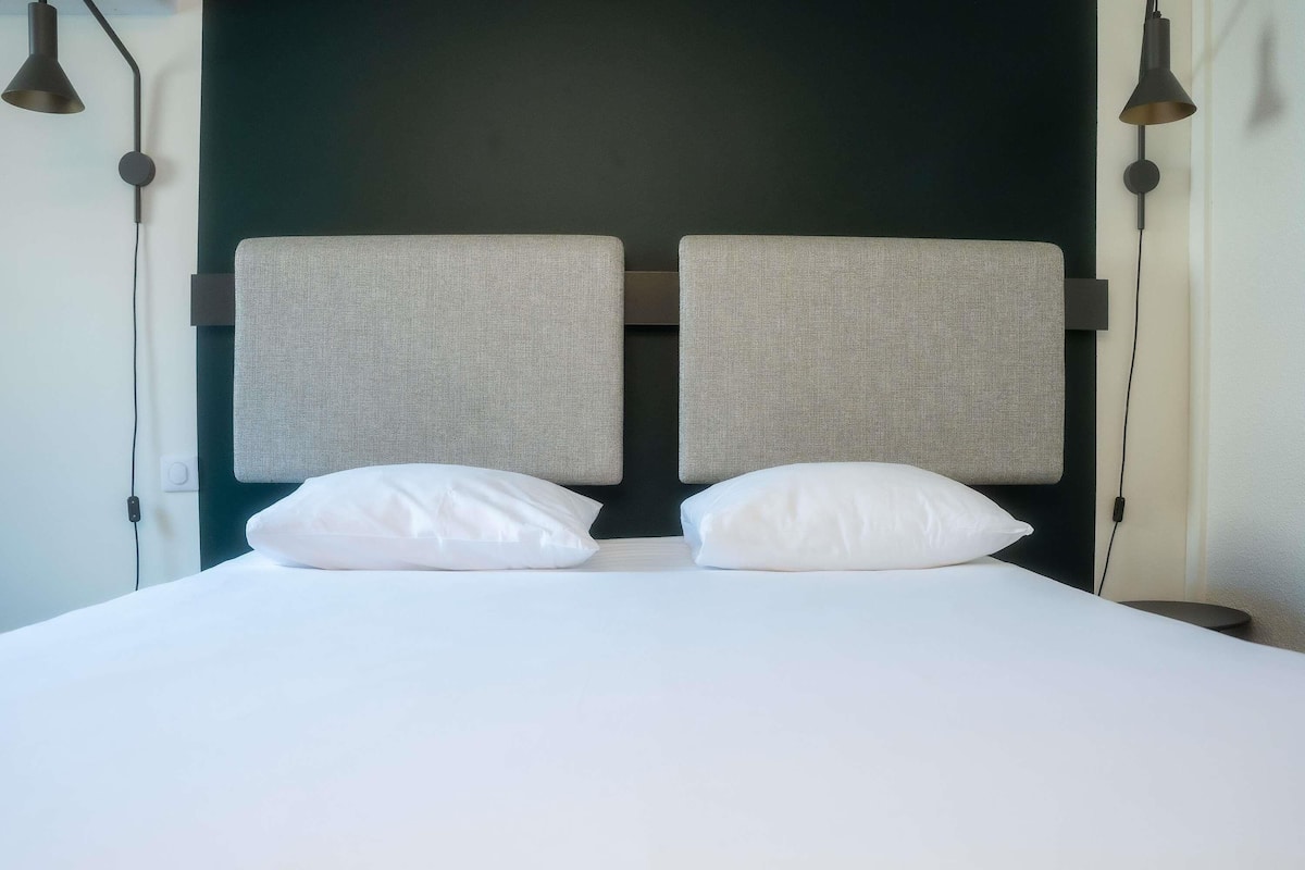 Ein Bett mit zwei Kissen, einem Kopfteil und zwei Wandleuchten.