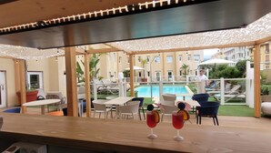 A wooden deck with outdoor seating, a pool, and a view of a residential building. - ibis Nice Centre Gare (Nice)