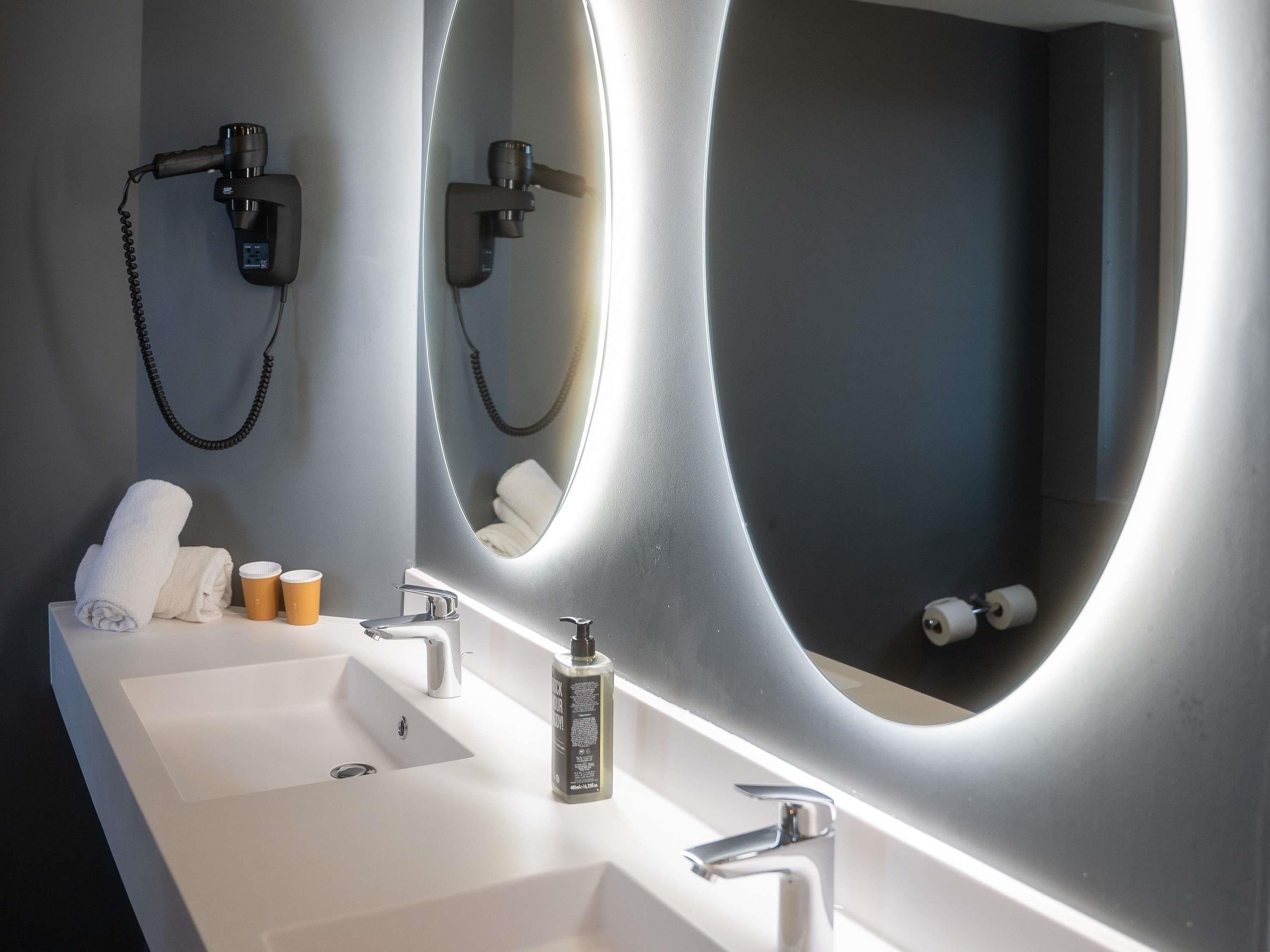 A bathroom with two sinks, a mirror, and a towel rack.
